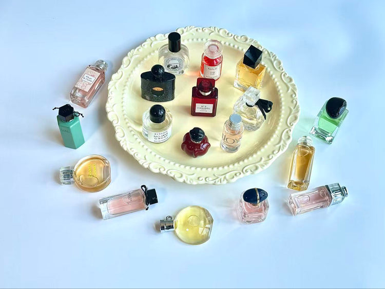 Collection of small perfume bottles arranged around a decorative plate on a light blue background